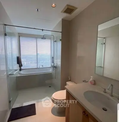 Modern bathroom with glass shower and city view, featuring sleek fixtures and natural light.