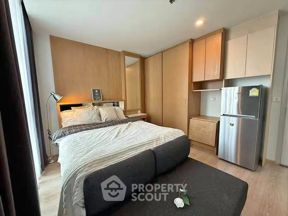 Modern bedroom with cozy bed and compact kitchen area in stylish apartment.