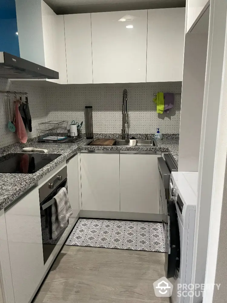 Modern compact kitchen with granite countertops and sleek white cabinets