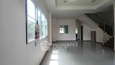 Spacious modern living room with large windows and staircase, perfect for family gatherings.