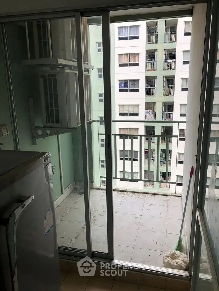 Compact balcony with sliding glass doors and view of neighboring building.