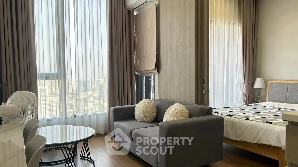 Modern apartment with large windows and cozy furnishings in a high-rise building.