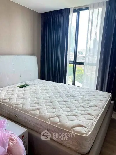 Cozy bedroom with large window and modern decor, offering a bright and inviting atmosphere.