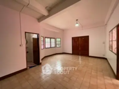 Spacious empty room with tiled floor and large windows, ideal for customization.
