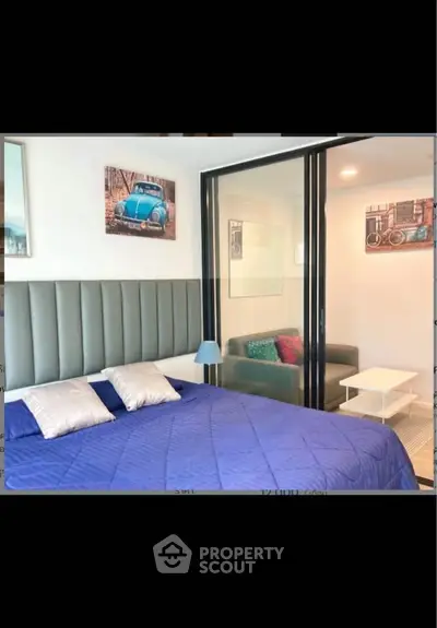 Modern bedroom with stylish decor and sliding glass partition to cozy sitting area.