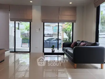Modern living room with sleek black sofa and large windows offering natural light