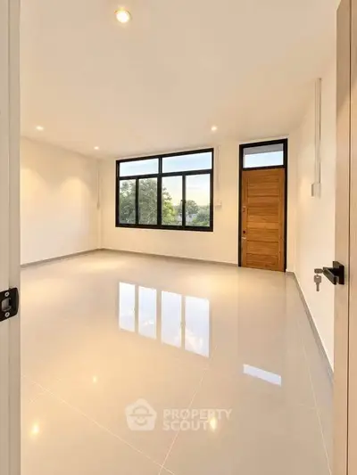 Spacious empty room with large windows and wooden door, perfect for customization.