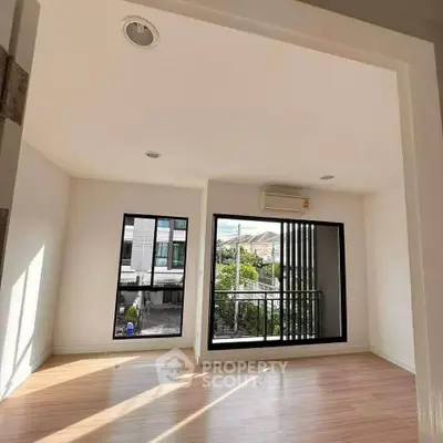 Bright and airy room with large windows and modern flooring, perfect for a cozy living space.