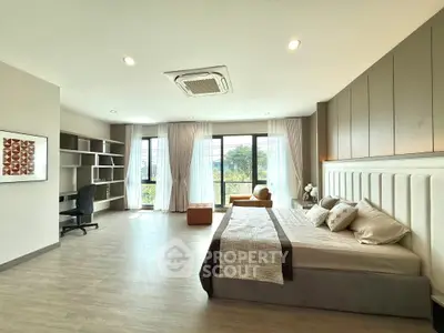 Spacious modern bedroom with large windows and stylish decor, perfect for comfort and relaxation.