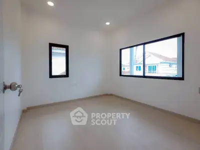 Spacious empty room with large windows and wooden flooring, perfect for customization.