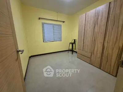 Spacious bedroom with wooden wardrobe and modern chair, perfect for cozy living.