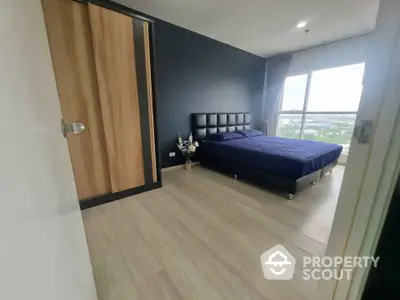 Modern bedroom with large window and city view, featuring a stylish bed and wooden wardrobe.