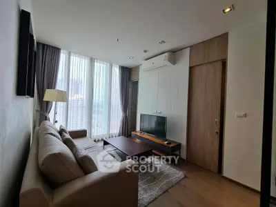 Modern living room with large windows and city view, featuring cozy sofa and sleek TV setup.