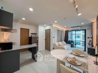 Modern open-layout living room and kitchen with stylish decor and natural light.