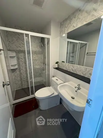 Modern bathroom with glass shower, sleek fixtures, and stylish tile design.