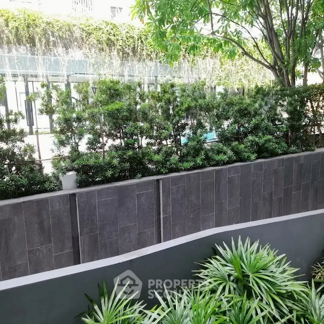 Lush garden view with modern stone wall and greenery, perfect for serene outdoor living.