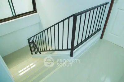 Modern staircase with sleek railing and glossy tiled flooring in a contemporary home.