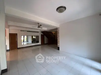 Spacious empty living room with tiled floor and ceiling fan, ready for customization.