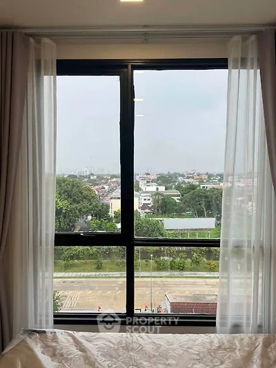 Spacious bedroom with large window offering a stunning city view, perfect for natural light lovers.