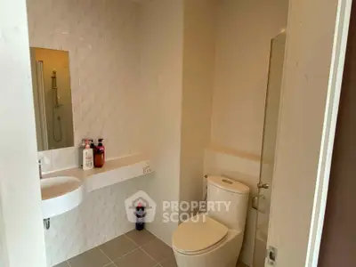 Modern bathroom with sleek sink and toilet, featuring a minimalist design.