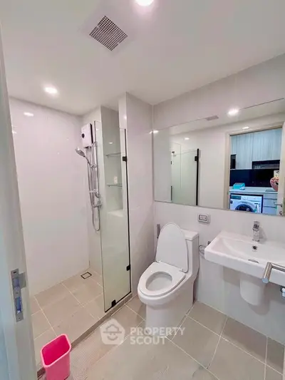 Modern bathroom with glass shower and sleek fixtures in contemporary apartment.