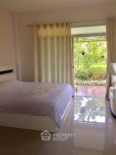 Bright bedroom with garden view and sliding glass doors opening to patio.