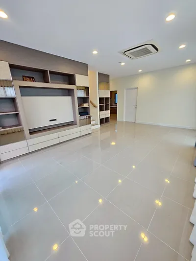 Spacious modern living room with built-in shelves and sleek tile flooring.