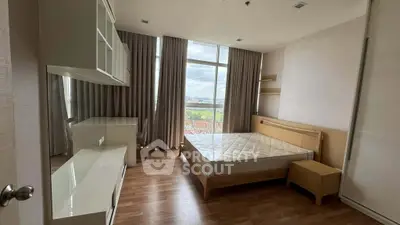 Spacious bedroom with large window offering stunning city view, featuring modern furniture and elegant wooden flooring.