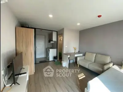 Modern living room with cozy sofa, TV, and washing machine in open layout apartment.