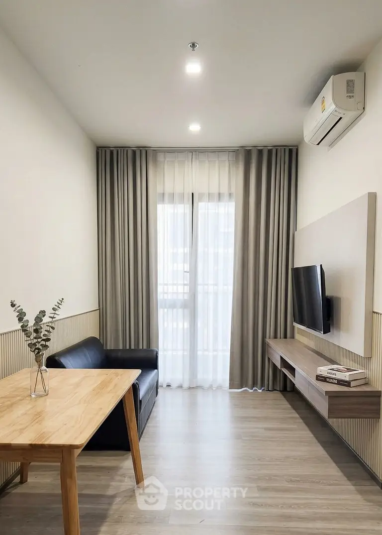 Modern living room with sleek furniture and natural light, featuring a wall-mounted TV and air conditioning.