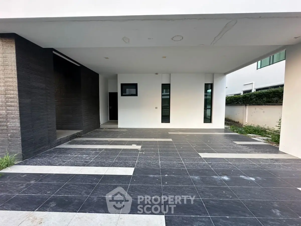 Modern covered parking area with sleek black and white tile design in contemporary home.
