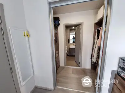 Modern walk-in closet leading to a stylish bathroom with sleek design.