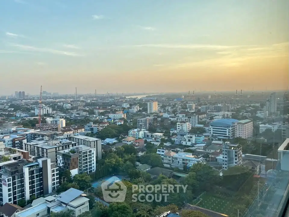 Stunning cityscape view from high-rise building at sunset, showcasing urban skyline and lush greenery.