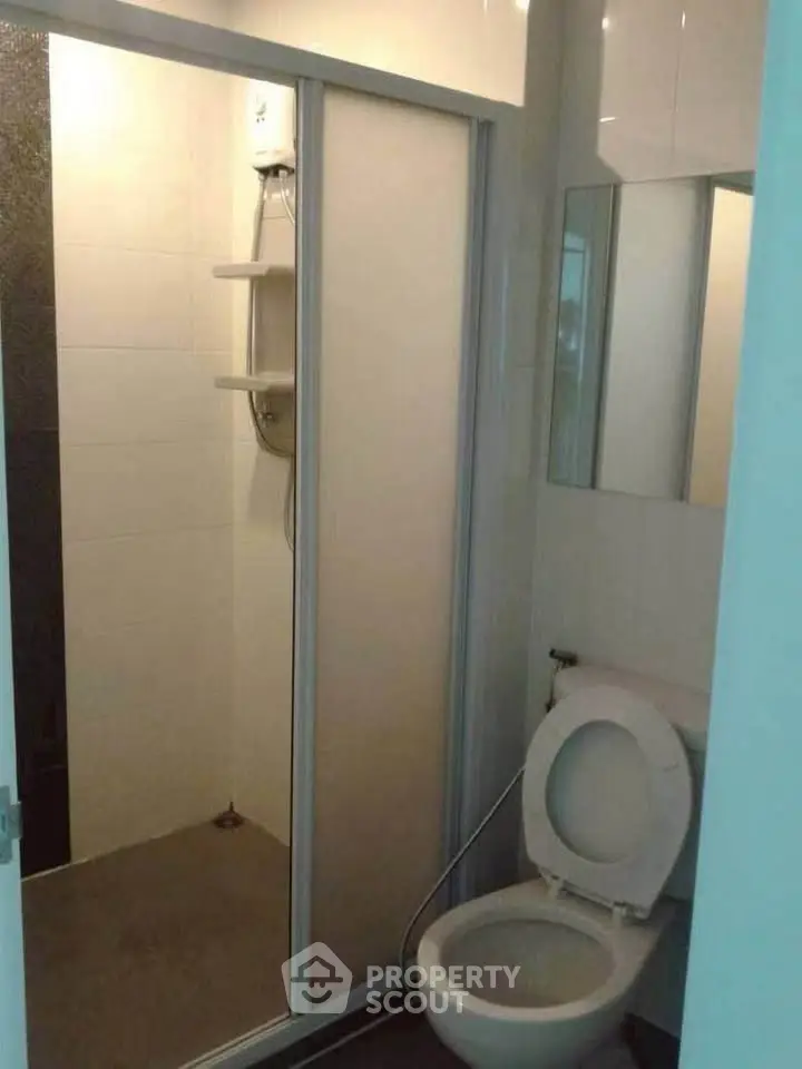 Compact bathroom with shower and toilet in modern apartment.