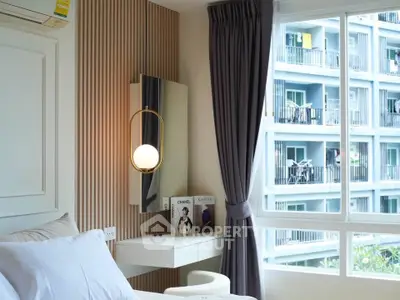Modern bedroom with stylish lighting and large window overlooking apartment complex.