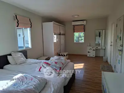 Spacious bedroom with natural light and modern decor, featuring wooden flooring and ample storage.