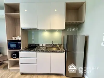 Modern kitchen with sleek cabinets, granite countertop, and stainless steel fridge