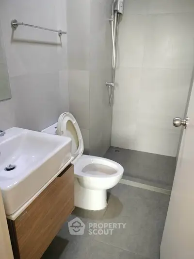 Modern bathroom with sleek fixtures and minimalist design, featuring a shower and compact sink.