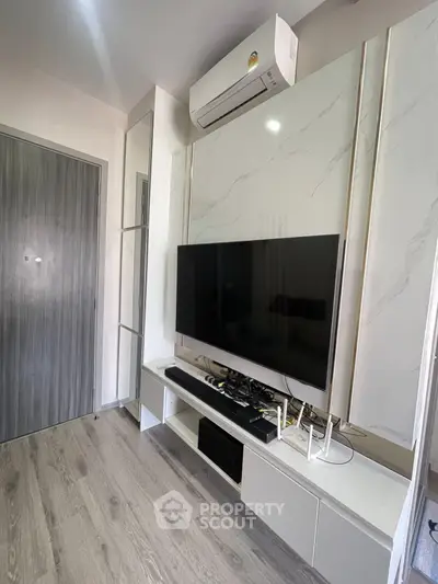Modern living room with sleek TV setup and air conditioning, featuring stylish flooring and contemporary design.