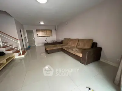 Spacious living room with modern sofa and sleek tile flooring in a contemporary home.
