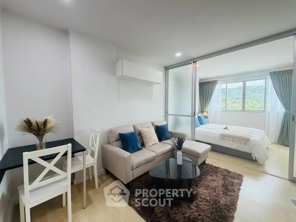 Modern open-plan living room with cozy seating and bedroom view, featuring elegant decor and natural light.