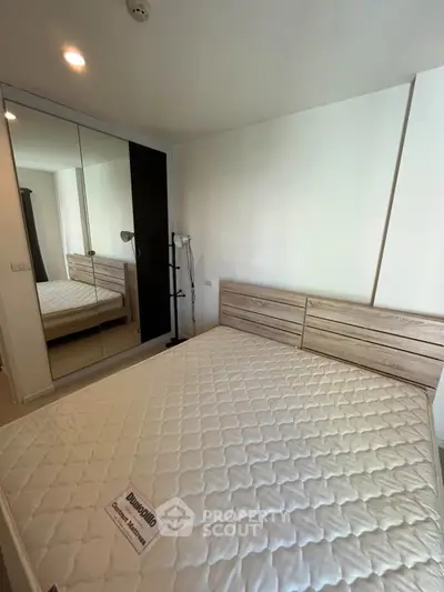 Modern bedroom with mirrored wardrobe and stylish bed frame, perfect for urban living.