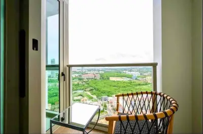 Stunning balcony view with modern chair overlooking lush greenery and cityscape.