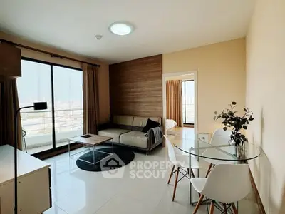 Modern living room with glass dining table and cozy sofa, featuring a balcony view.