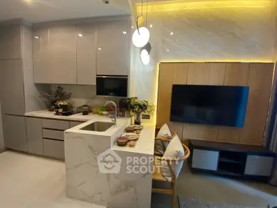 Modern kitchen with marble countertops and integrated living area featuring sleek TV setup.