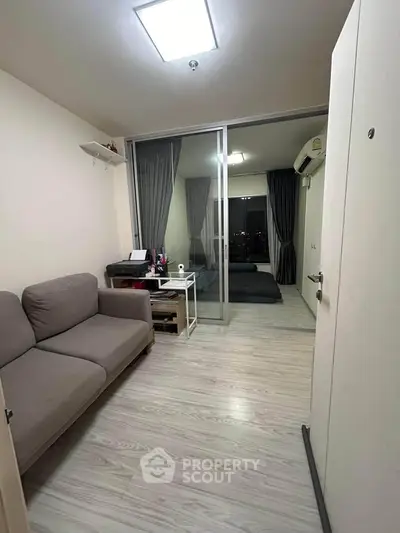 Modern apartment interior with cozy living room and bedroom separated by glass sliding doors.