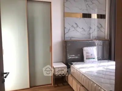 Modern bedroom with stylish marble accent wall and sliding closet doors.