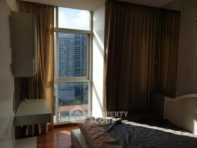 Spacious bedroom with large window offering stunning city view and natural light.