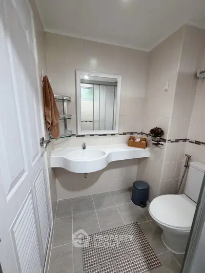 Modern bathroom with sleek fixtures and neutral tiles, featuring a stylish sink and toilet.