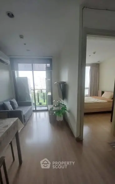 Cozy apartment interior with living room and bedroom view, featuring a balcony and modern decor.